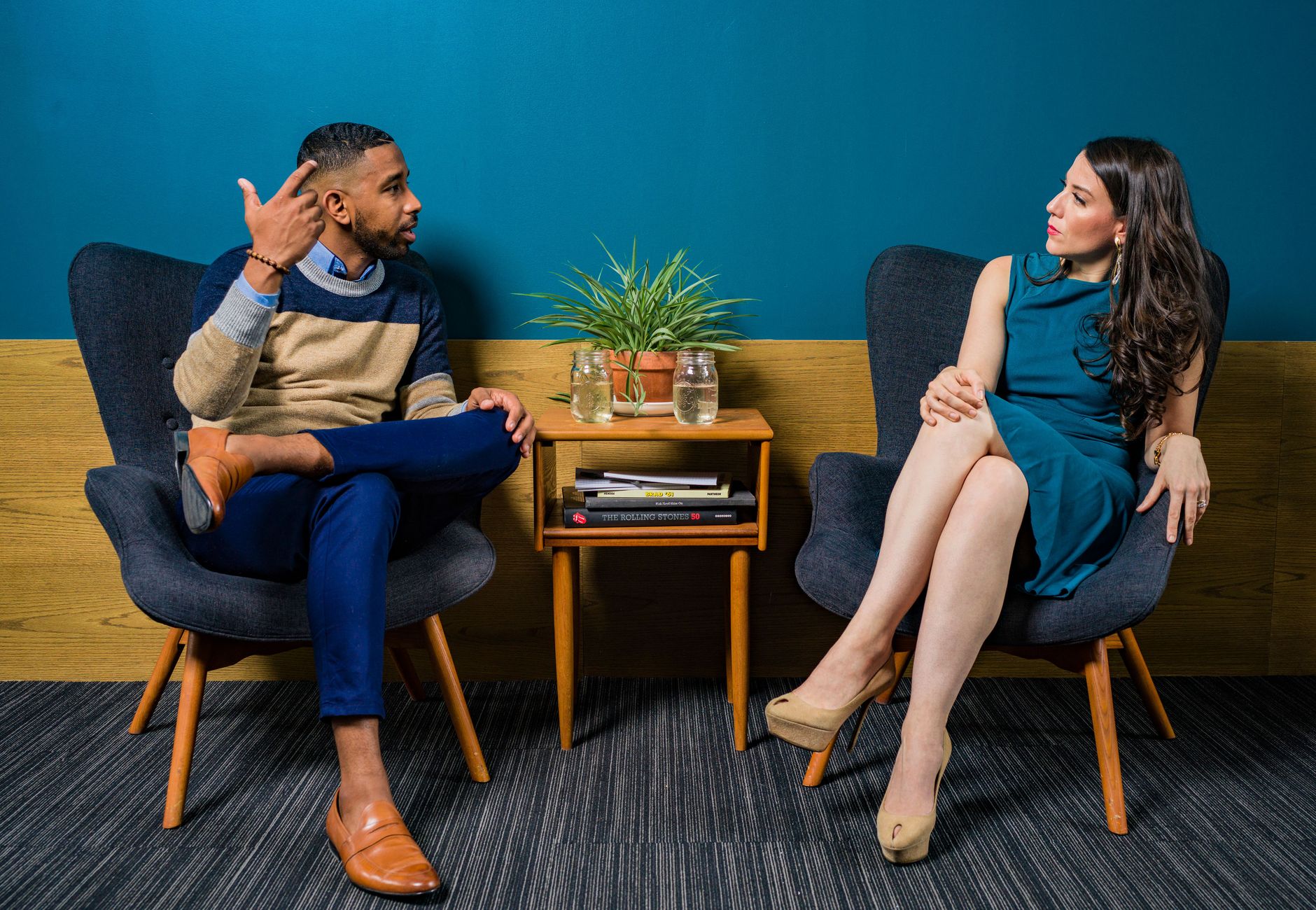 Two professionals in business attire engage in a thoughtful discussion sitting in a stylish, modern room.