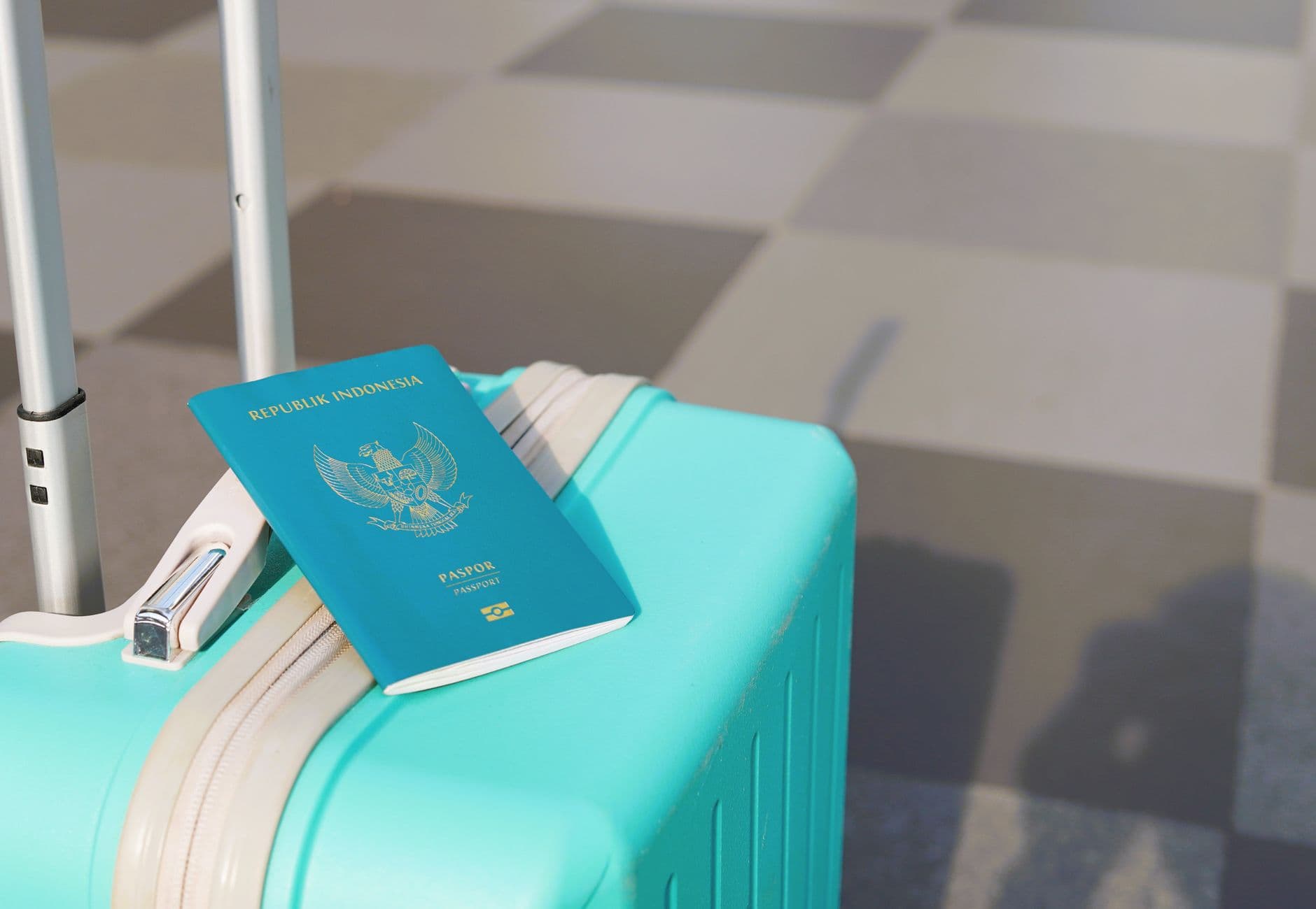 Indonesian passport resting on a turquoise suitcase, symbolizing international travel.