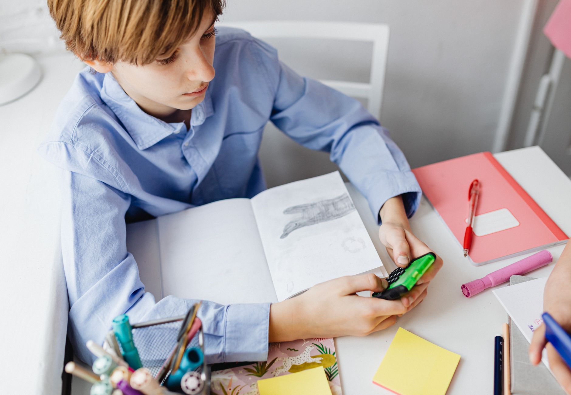 Boy using a calculator while studying at a desk with school supplies, focusing on mathematics.
