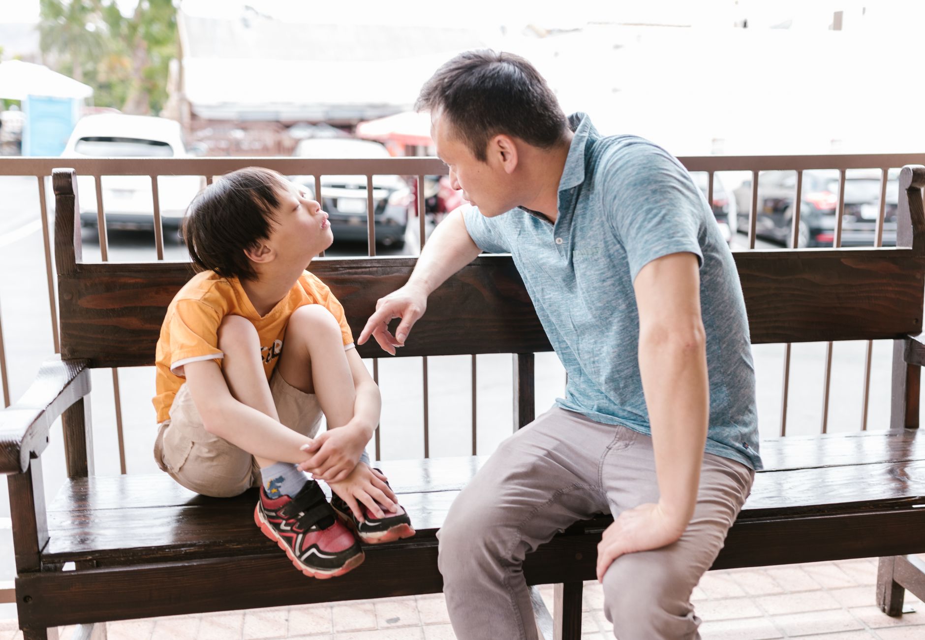 A heartfelt interaction between father and son sitting on a wooden bench outdoors, promoting bonds and autism
