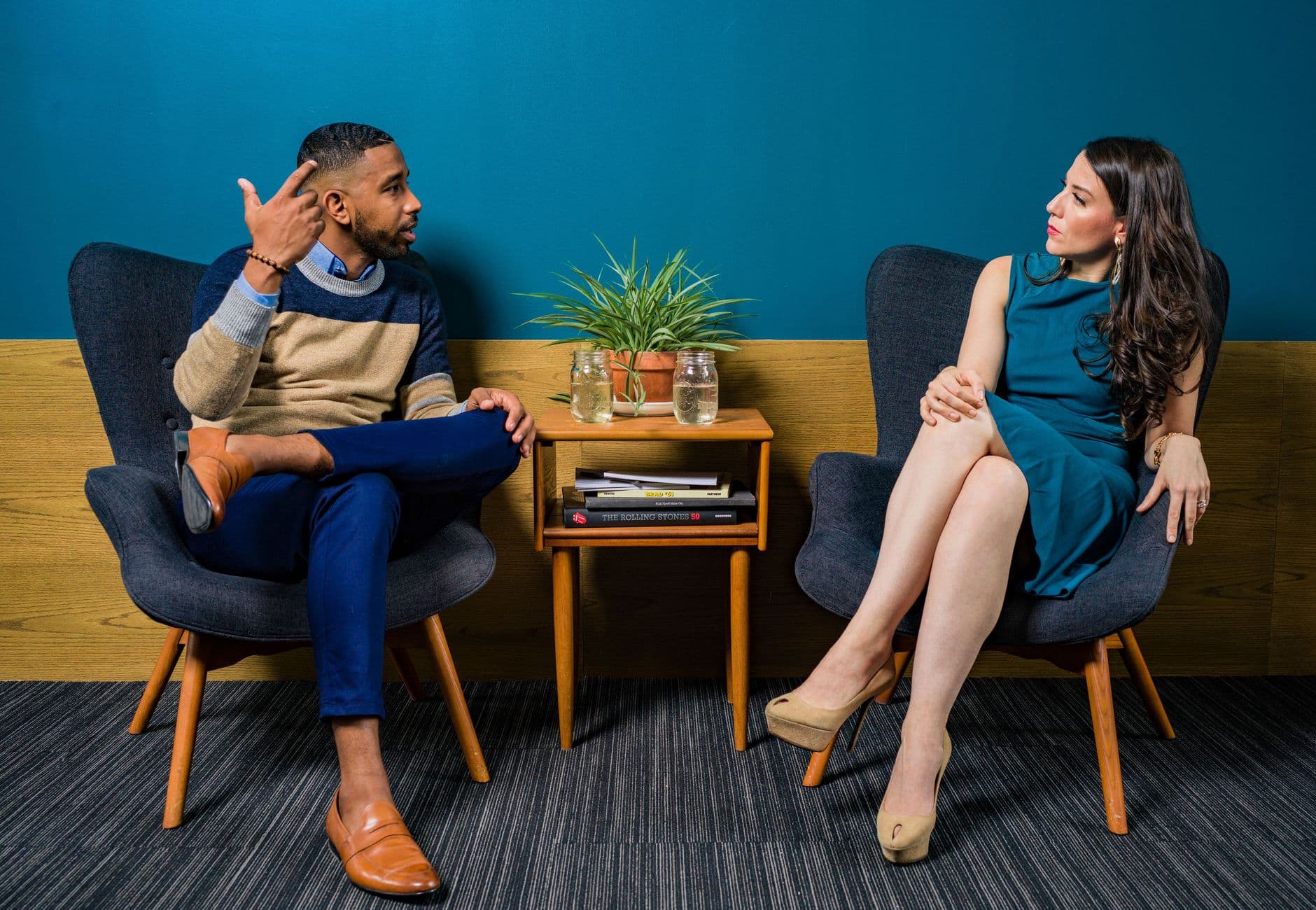 Two professionals in business attire engage in a thoughtful discussion sitting in a stylish, modern room.