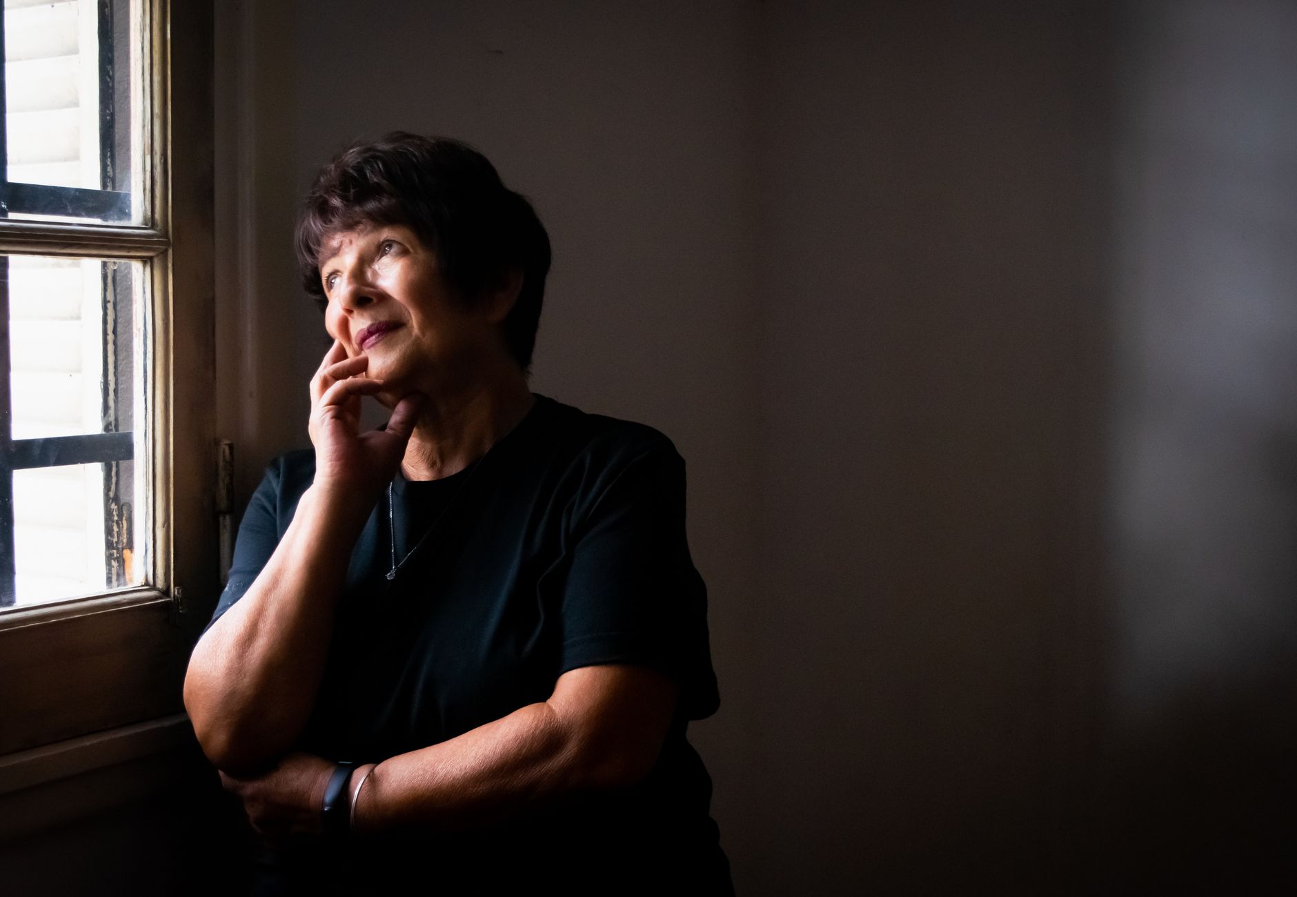 Thoughtful senior woman looking out a window, lost in reflection and quiet contemplation.