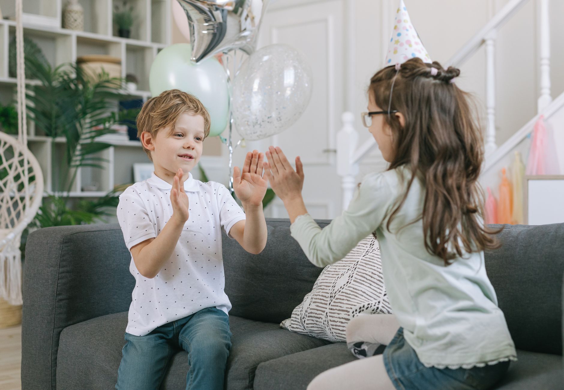 Children joyfully playing clapping games at a birthday party indoors.